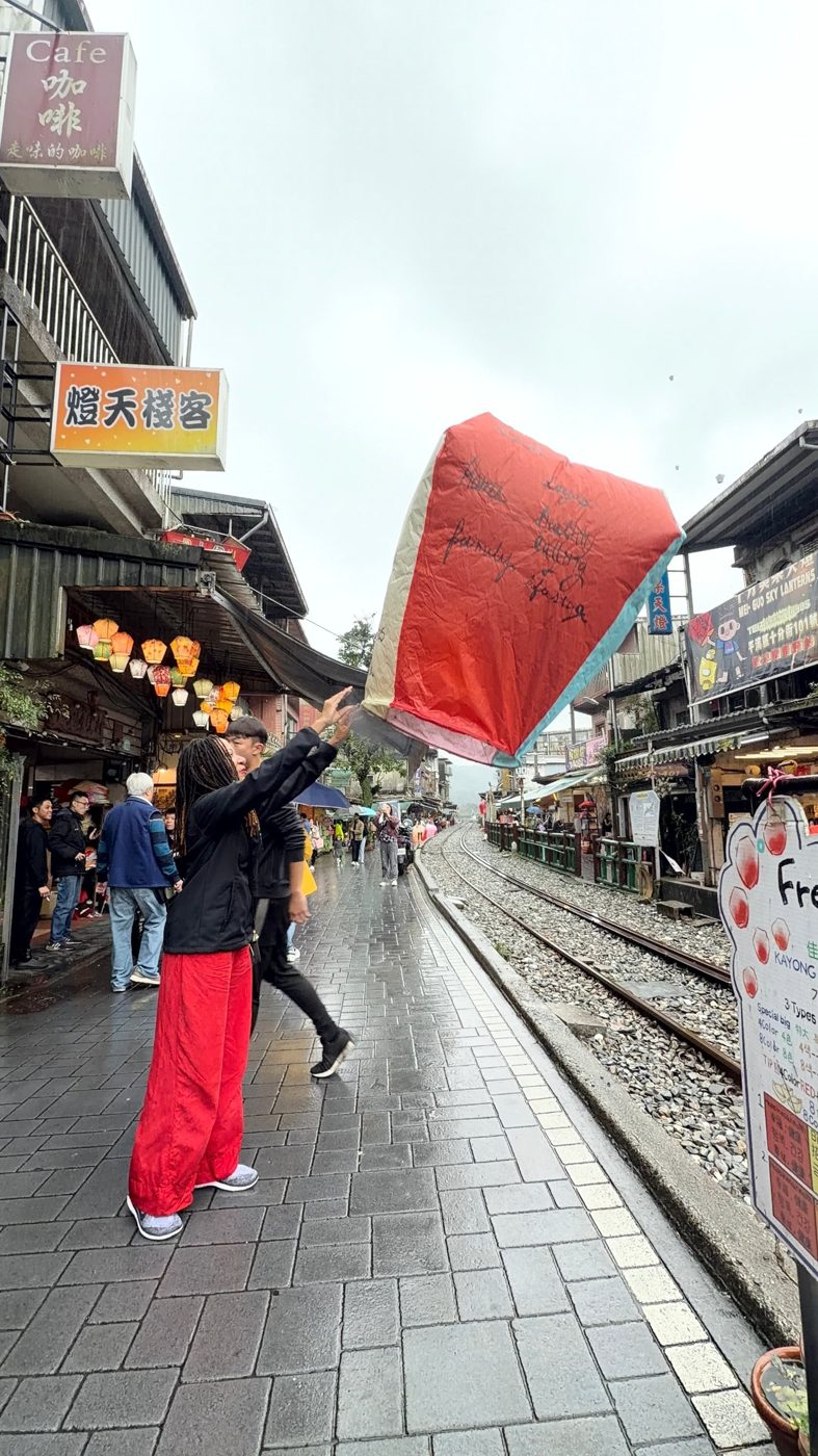 Brittney releasing a red sky lantern beside train tracks