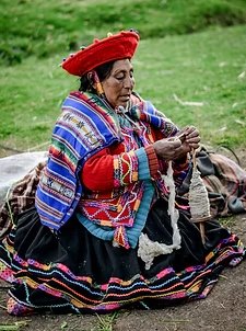 A Quechua woman in traditional dress spinning wool